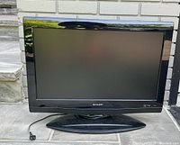Front view of Sharp 26 inch LCD TV showing screen and base stand.