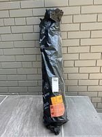 Full view of the vapor barrier roll still wrapped in black packaging against a brick wall.