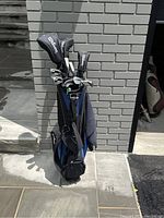 Front view of stand bag with clubs leaning against brick wall