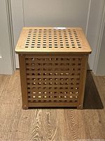 Front view of the pine wood storage table showing lattice design on front panel and metal fasteners at corners