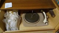 Top view of the wooden cabinet with the turntable visible inside, partially covered with tissue paper on one side.