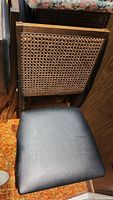 Close-up of the seat and woven cane backrest of one folding chair.