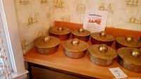 Eight brass gongs arranged on wooden surface against wallpapered wall
