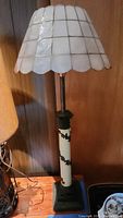 Tall table lamp with metal base and scalloped white shade
