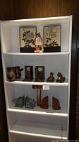 Full view of white bookcase containing all items including Lenox owl figurine, brass bookends, and wall plaques.