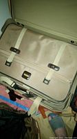 Open 28 inch Samsonite suitcase interior showing beige fabric, white securing straps, and metal buckles