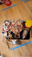 Photo showing multiple small dolls and three small carts or wagons including wooden and plastic ones, arranged on the floor.