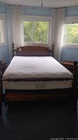 Full view of the bed in a room showing mattress, headboard, and part of footboard.