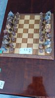 Chessboard set up with all chess pieces arranged in starting positions on the board, displayed on a wooden table.
