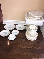 Photo shows six pieces of a Portugal china set including dinner plate, soup bowl, bread and butter plate, dessert plate, cup, and saucer. The pieces are white porcelain with a light blue floral pattern and ornate embossed edges.
