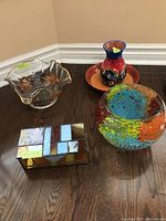 Full view of two glass bowls, ceramic vase with matching tray, and stained glass style decorative box on wooden floor