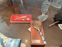 Photo shows magnifying glass with ceramic handle, crystal perfume bottle, and boxed scissors with thimble on table.