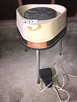 Front view of the electric potter's wheel on tripod legs with foot pedal attached
