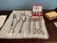 Full lot on lace-edged cloth: six silver plate serving utensils and Leonard salt and pepper set in box
