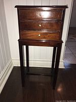 Front view showing entire side table with 3 drawers and wooden legs.