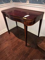 Front-left three-quarter view showing curved top, inlay banding, tapered legs