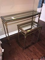 Two matching metal frame tables with glass tops showing size difference and overall design.
