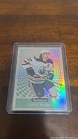 Holographic Connor McDavid Parkhurst trading card in hard plastic case on wooden table