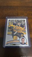 Photo of Connor McDavid rookie hockey card in protective case, card shows player in yellow Oilers jersey with a smaller portrait inset.