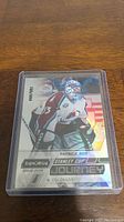 Single photo of Patrick Roy short print hockey card 785/999 in plastic sleeve placed on wooden surface.