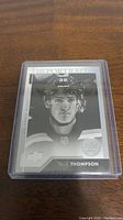 Black and white close-up of Tage Thompson rookie hockey card from Upper Deck Portrait series in protective case.