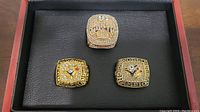 Three replica championship rings displayed in a black presentation box: two gold-tone Toronto Blue Jays rings for 1992 and 1993 World Series and one gold and silver-tone Toronto Raptors 2019 Championship ring.