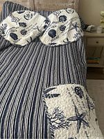 Close-up of white and navy sea life print bedspread with striped backing on the edge, laid over bed