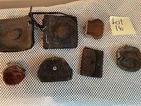 Overview of all 7 coin purses including two larger ones with US embossed rosettes and five smaller leather coin purses of various shapes and sizes