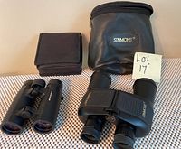 Two pairs of binoculars displayed with their carrying cases: Simmons 8x40 and Orion 8x32