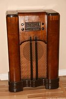 Full view of the 1938 RCA Victor console radio in a dark wood cabinet with cylindrical side columns and cloth speaker grille