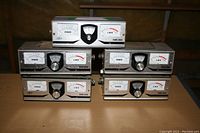 All six OSKERBLOCK SWR-200 antenna tuners arranged in two rows on table, showing front panels with power and SWR meters and central dial knobs