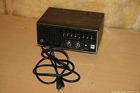 Realistic Pro-52 Police Scanner Patrolman unit showing front panel with power cord on wooden table, wood grain finish, and control switches.