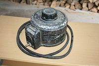 Full view of the Variac variable transformer showing circular metal housing, black finish with wear, adjustment dial, and attached power cord.