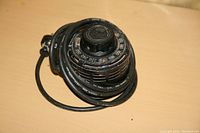 Photo of a black variac voltage regulator with large black power cord coiled around it on a wooden surface.