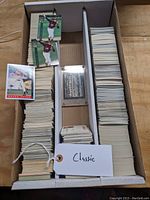 Large collection of vintage baseball cards stored in a divided white box with a Classic tag. Cards are stacked in three compartments with some organized in bundles and loose cards on top.