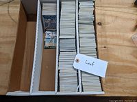 A box with three rows filled with neatly organized baseball cards labeled 'Leaf' on a tag.