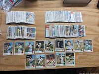 Full layout of multiple stacks of vintage 1973 Topps baseball cards spread on a wooden surface.
