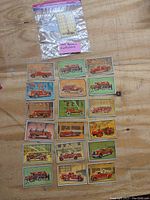 Set of 18 vintage 1953 Bowman Firefighters trading cards spread out on a wooden surface showing various illustrated fire trucks and firefighting scenes.