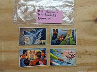4 vintage trading cards featuring jets, rockets, and spacemen from 1951 Bowman series laid out on table with original bag and label