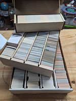 Wide shot of the assortment of football cards stored in cardboard trays and boxes on a wooden surface.