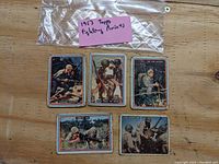 Five 1953 Topps Fightin' Marines trading cards laid out on wood surface with a plastic bag and note showing series name.