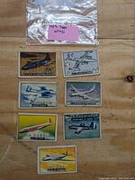Seven 1952 Topps Wings trading cards laid out on a wooden surface. Cards depict various aircraft and are in worn condition with some creasing visible.