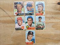 Seven vintage Topps baseball cards laid out on wood surface. Cards show players Chuck Dressen, Jim Hearn, Clint Courtney, Karl Drews, Fred Hutchinson, Jim Waugh, and Vic Wertz. Cards have visible wear and creases.
