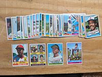 Collection of approximately 50 1976 Topps baseball cards laid out on a wooden surface, showing multiple player cards including Willie Randolph, Fred Box, and others.