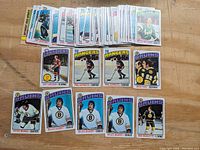 Photo showing multiple 1976 Topps hockey cards spread out. Cards include players Peter McNab, Gilles Gilbert, Brad Park, Don Marcotte, Phil Esposito, Guy LeFleur and others. Some cards have duplicates.