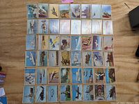 Full spread of the 1954 Bowman Power for Peace cards laid out on a wooden surface, showing multiple rows of colorful vintage military aircraft and naval themed cards.