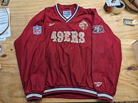 Front view of red pullover jacket with embroidered 49ers text, NFL and 49ers patches.