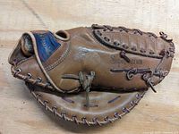 Photo of the left-hand vintage Spalding first baseman's mitt showing the outer side with brand and model markings, brown leather, and laced pocket.
