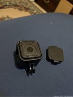 Front view of small black cube-shaped GoPro HERO Session camera showing lens and separate lens cover.