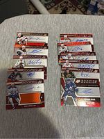 Photo showing two groups of hockey cards with autographs and memorabilia swatches on a beige cloth surface.